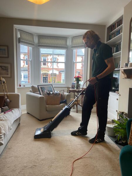 Nathan vacuuming a living room carpet.